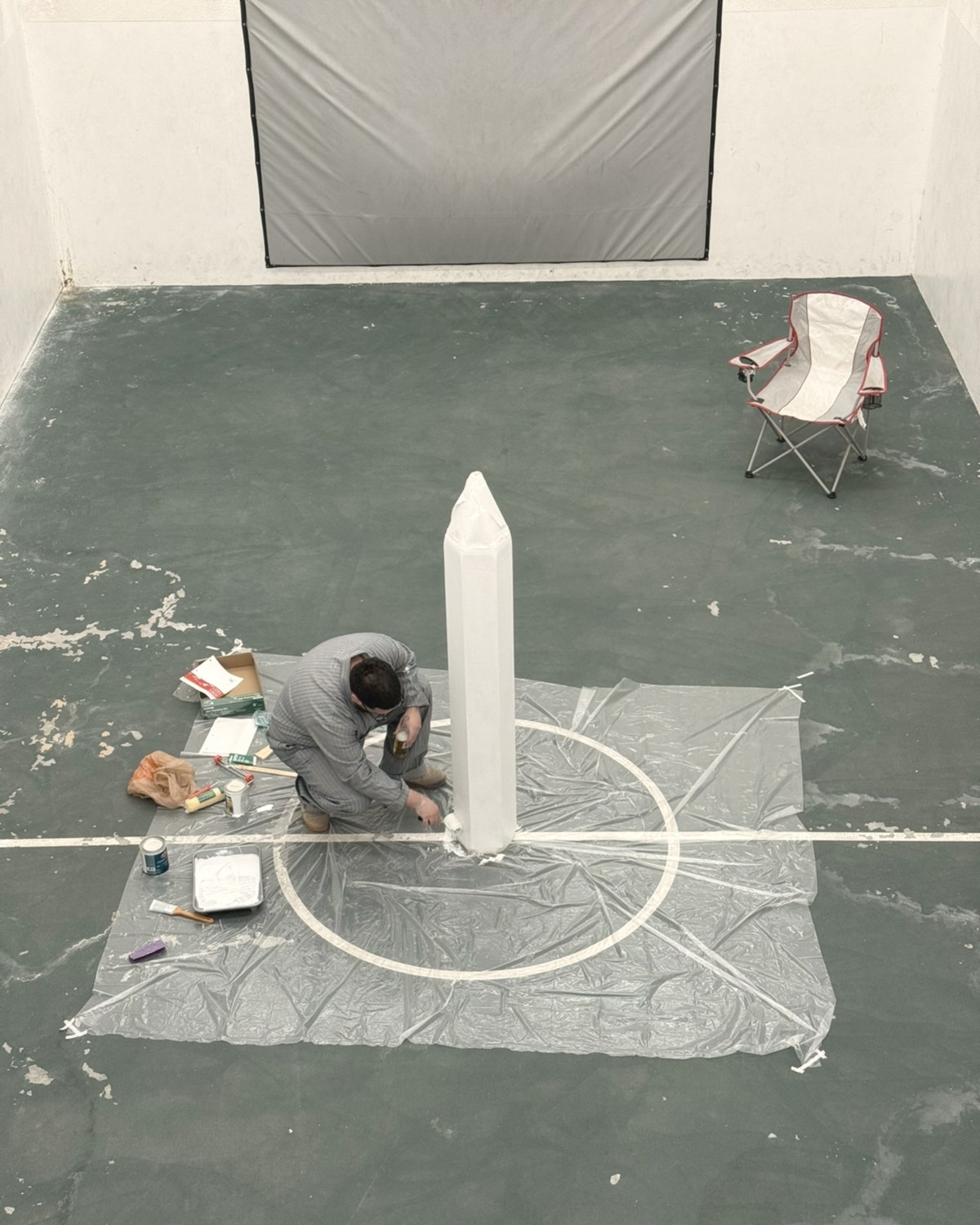 Miguel Najarian in the studio, crouched at the base of the pencil sculpture, painting it